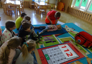 Ratownik uczy dzieci ułożenia w pozycji bocznej bezpiecznej